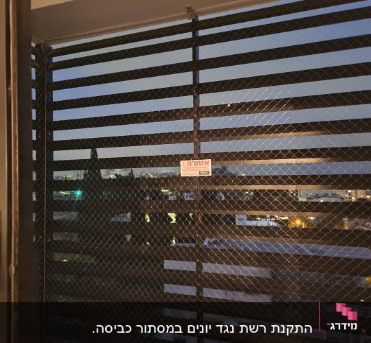 רשת יונים מותקנת על חלון עם נוף עירוני